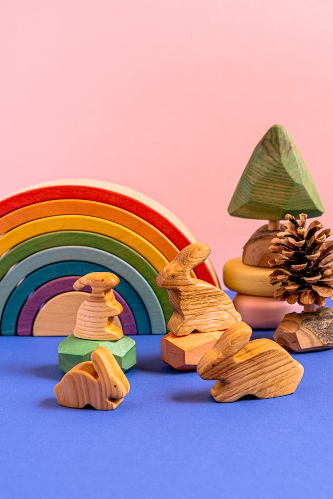 Charming wooden animal figurines with a colorful rainbow in a playful still life setup.